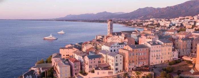Panorama de Bastia au soleil couchant avec les maisons pastel dominant le littoral.