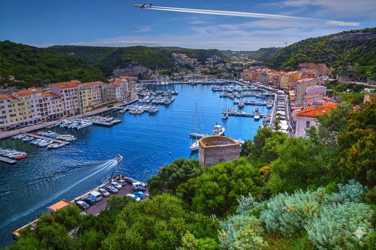 Vue aérienne du port de Bonifacio, avec yachts et citadelle en arrière-plan.