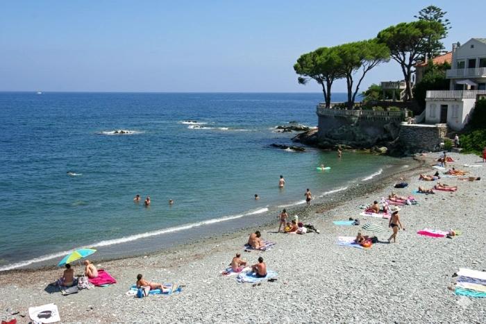 Plage du littoral de Bastia avec baigneurs, eau calme et maisons en bord de mer.
