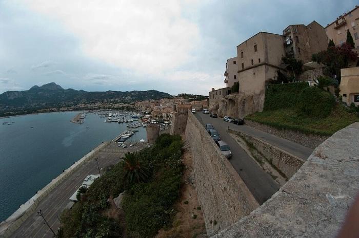 Vue des remparts de Calvi surplombant le port et la baie, avec les montagnes en arrière-plan